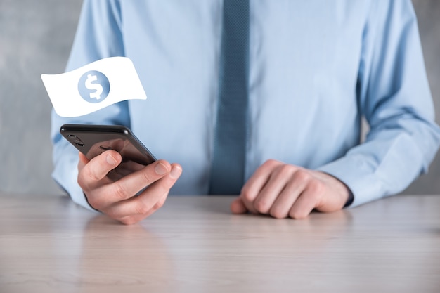 Businessman man holding money coin icon in his hands.Growing money concept for business investment and finance. USD or US dollar on dark tone background.