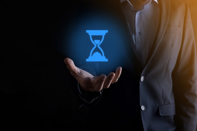 Businessman man holds in hand hourglasses icon. Time expires. A reminder to action. Business concept. Elements for design.