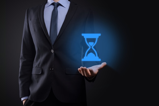 Businessman man holds in hand hourglasses icon. Time expires