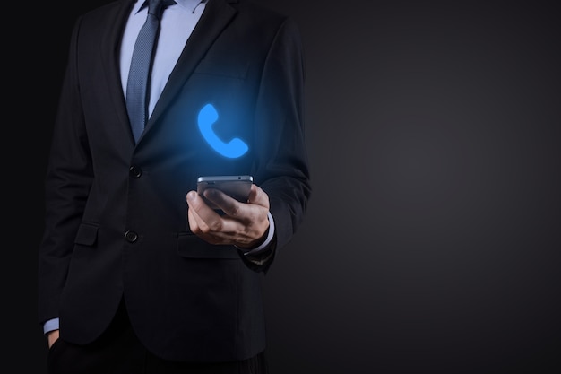 Businessman man in suit on black background hold phone icon.Call Now Business Communication Support Center Customer Service Technology Concept.