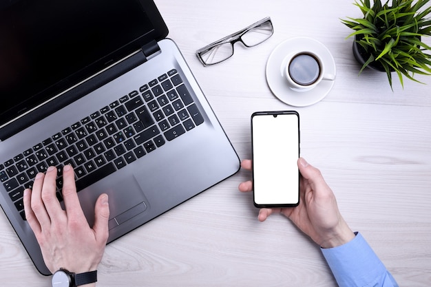 Businessman, man works at desktop on laptop and uses mobile phone.