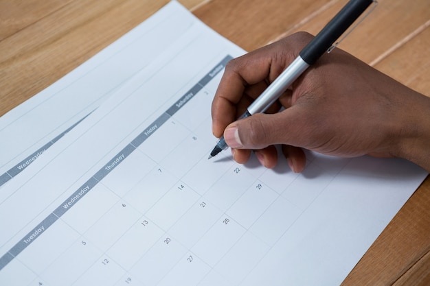 Foto marcatura dell'uomo d'affari con la penna sul calendario