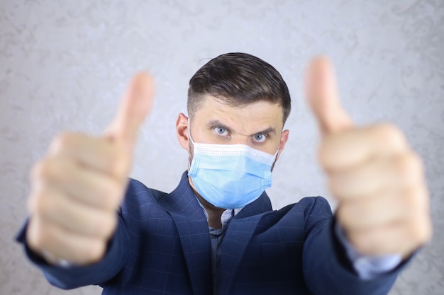 a businessman in a medical mask holds out his hands and makes a stop gesture