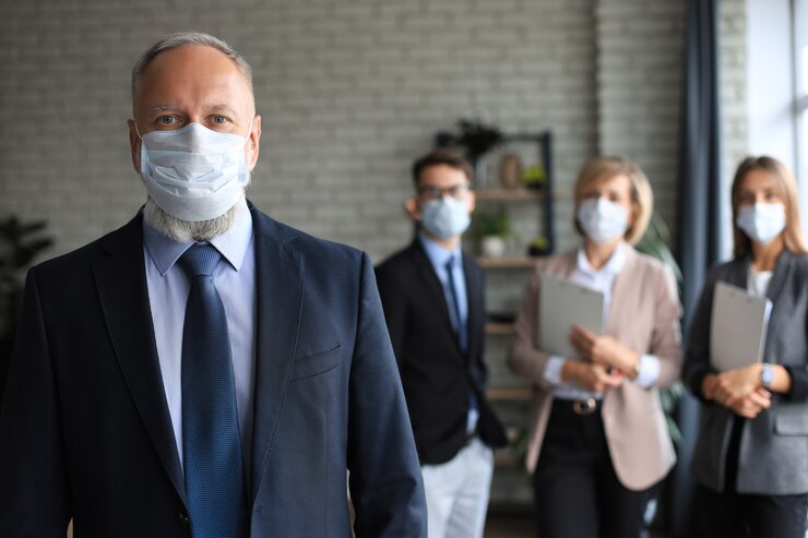 Photo businessman in medical mask with colleagues in the background in office.