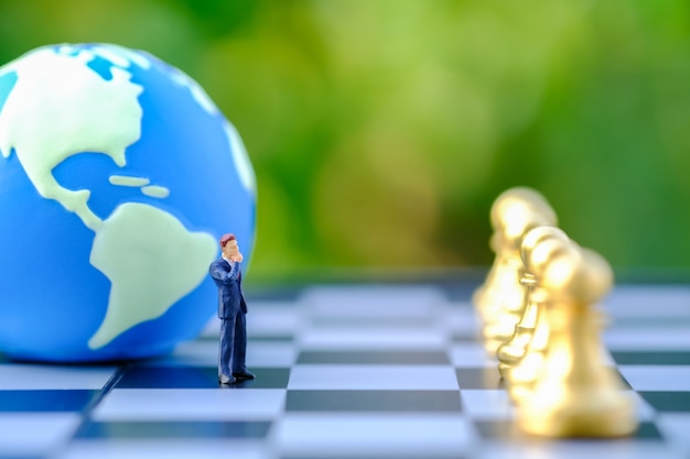 Foto imprenditore figura in miniatura persone in piedi sulla scacchiera con mini world ball