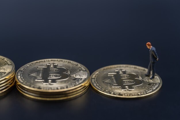 Businessman miniature figure people walking on stack of gold bitcoin coins