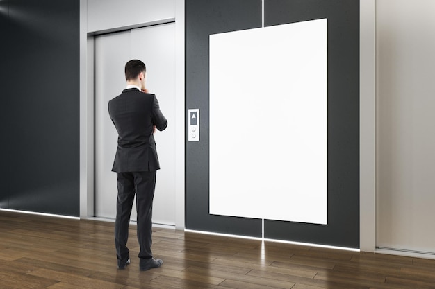 Foto uomo d'affari in moderno interno in cemento con ascensori poster bianco vuoto e pavimenti in parquet in legno lobby dell'ascensore e concetto di start up