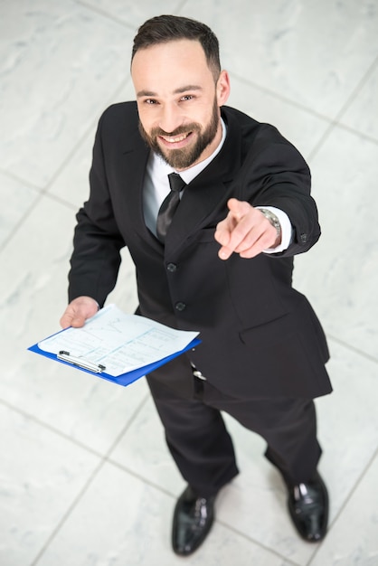 Businessman in modern office is looking at camera.