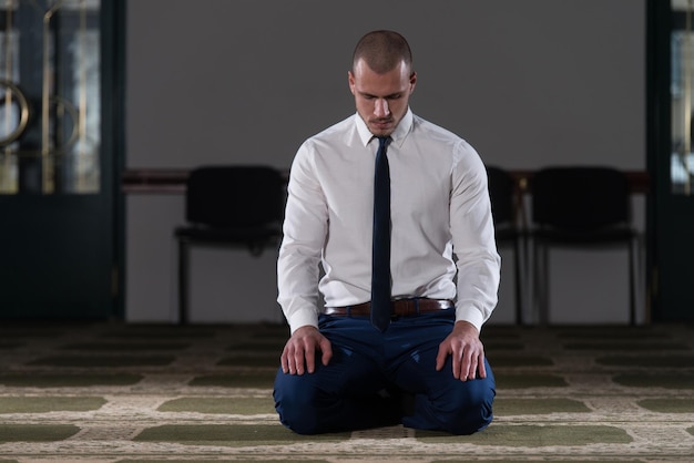 Бизнесмен-мусульманин совершает традиционную молитву Богу Аллаху в мечети