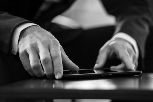 Businessman navigating a tablet computer while surfing the internet in greyscale