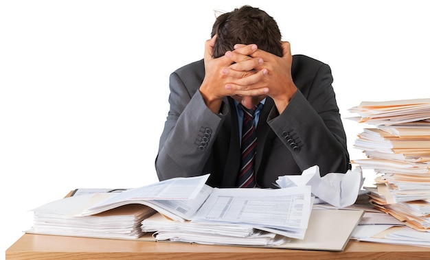 Businessman near heap of papers on background