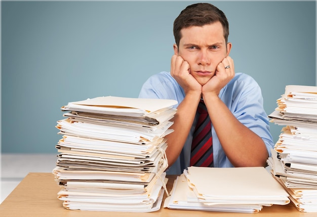 Businessman near heap of papers  on background