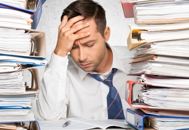 Businessman near heap of papers  on background