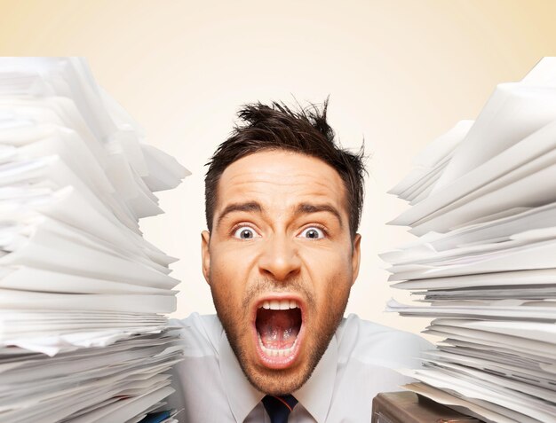 Businessman near heap of papers on background