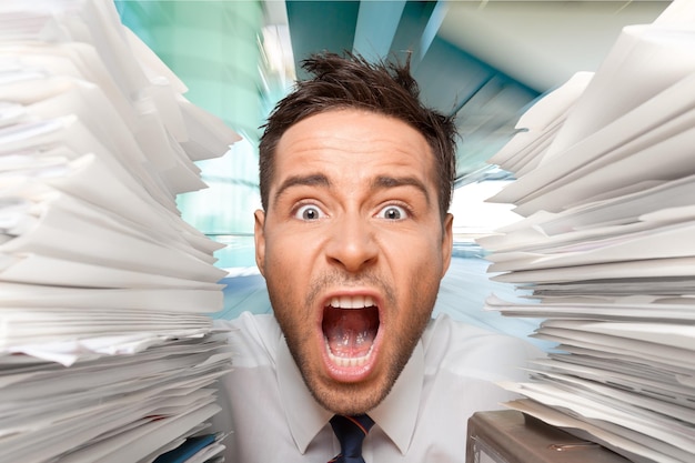 Businessman near heap of papers on background