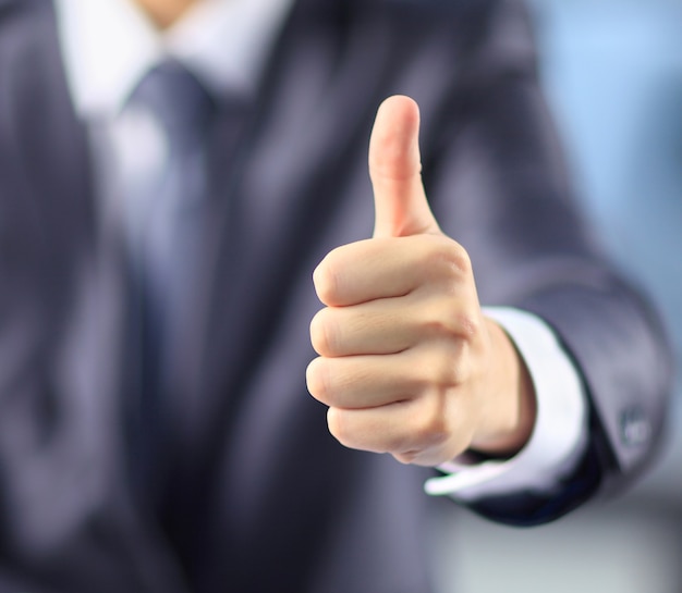 Businessman in the office of the shows his thumb on top.