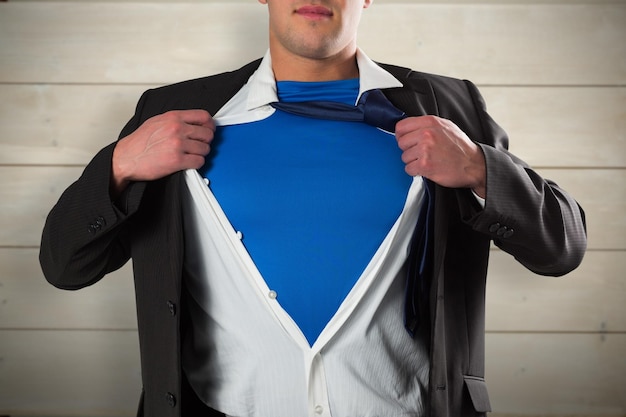 Businessman opening his shirt superhero style against bleached wooden planks background