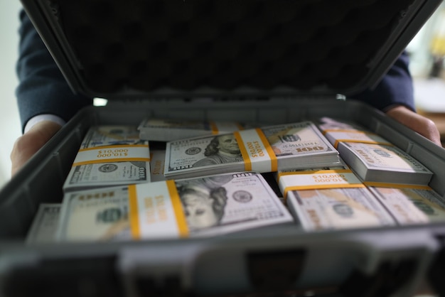 Businessman opens big suitcase with stacks of dollar bills in office successful man