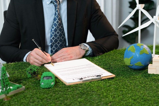 Фото Бизнесмен или исполнительный директор в офисе подписывает соглашение о регулировании окружающей среды для спасения земли с помощью устойчивого использования энергии и сокращения co2 для более зеленого будущего