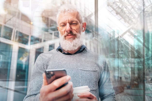 L'uomo d'affari fuori dall'ufficio legge la posta elettronica dallo smartphone