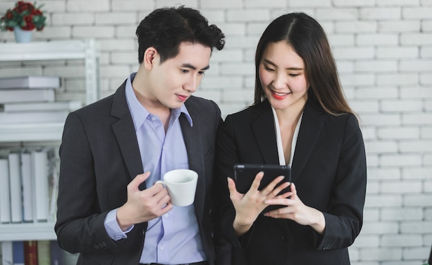 Businessman partners while working together with a tablet and businessman holding a cup