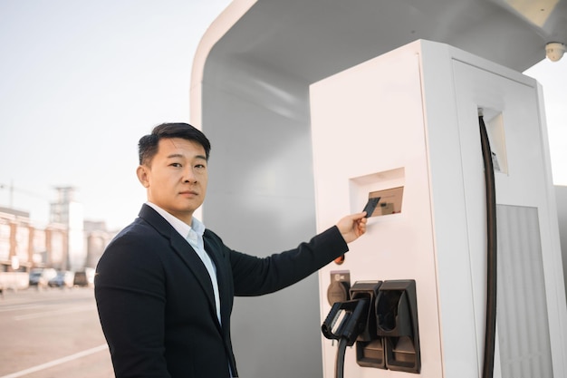 Businessman paying with card for charging electro car