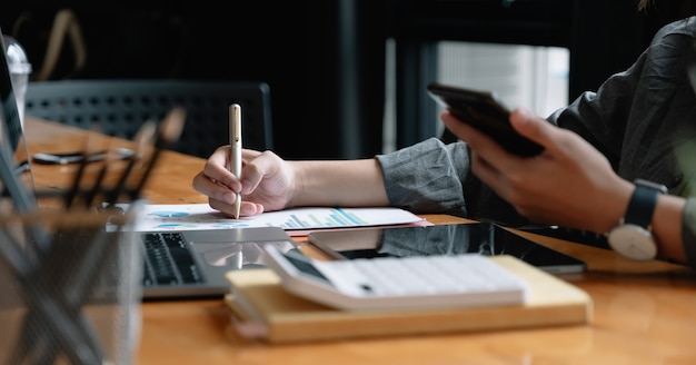 Businessman pen pointing turnover with graph chart report and use laptop computer for analysis data.