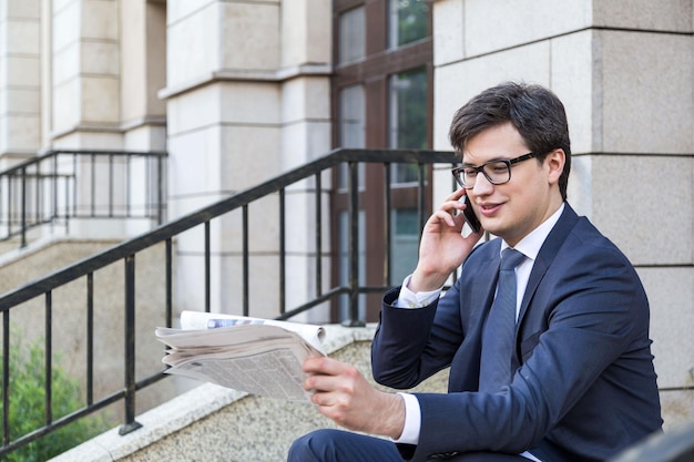 Businessman on phone reading newspaper