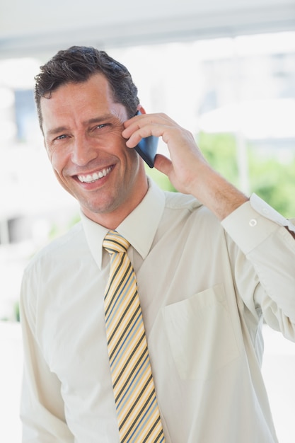 Foto uomo d'affari al telefono sorridendo alla telecamera