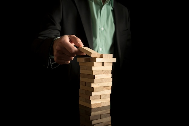 Businessman placing wooden block in a tower