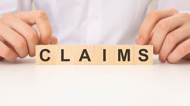 Businessman placing the wooden cubes with the word claims business program or meeting agenda concept