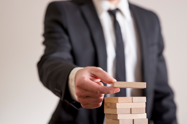 Uomo d'affari che mette domino di legno in una torre