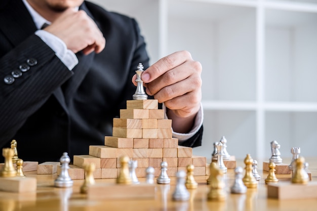 Uomo d'affari che gioca il gioco degli scacchi all'analisi di sviluppo nuovo piano di strategia