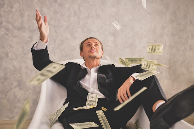 Businessman playing with paper currency while sitting on chair in office