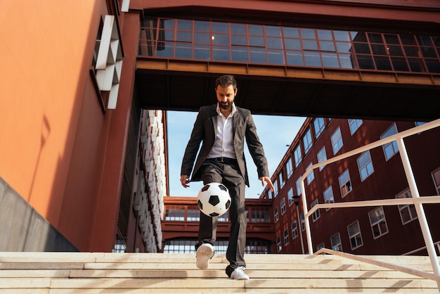 サッカー ボールで遊んで、フリー スタイルのトリックを作るビジネスマン