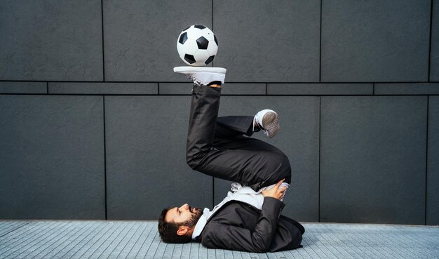 Бизнесмен играет с футбольным мячом и делает трюки фристайлом