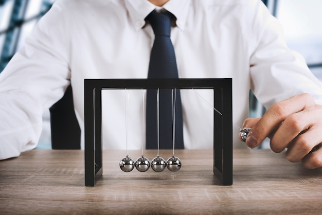 Businessman plays with the pendulum of Newtown balls