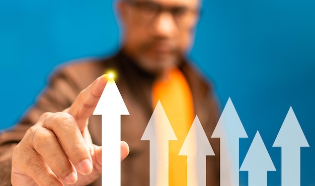 Photo businessman pointing an arrow going up interest finance banking economy stock market oil gas petroleum concept closeup selective focus copy space on right for text blue blurred background