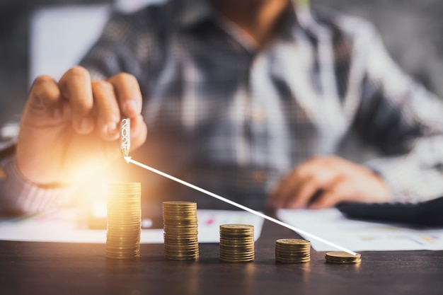 Businessman pointing on arrow graph on stacked coins