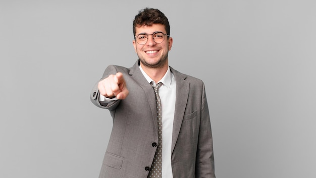 Businessman pointing at camera with a satisfied, confident, friendly smile, choosing you