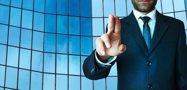 Businessman pointing finger next to building