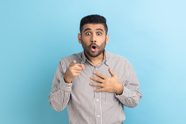 Businessman pointing fingers at camera and looking with big eyes and open mouth unbelievable news