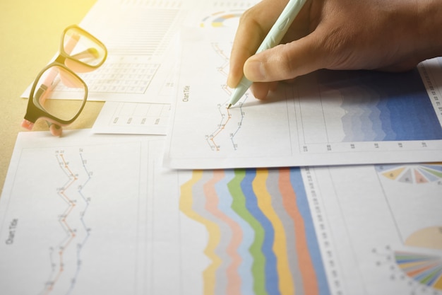 Businessman pointing graphs and chart on desk.