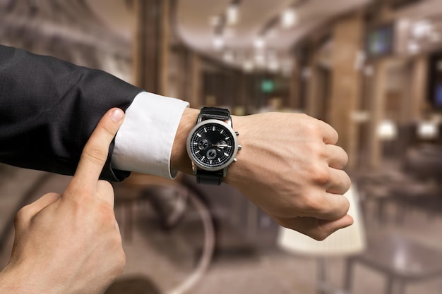 Businessman pointing at hand watch, close-up view