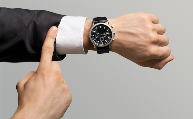 Businessman pointing at hand watch on grey