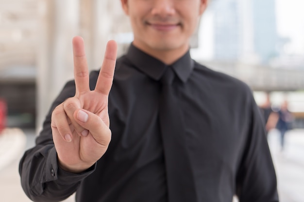 Businessman pointing up number 2 finger hand gesture, v sign victory