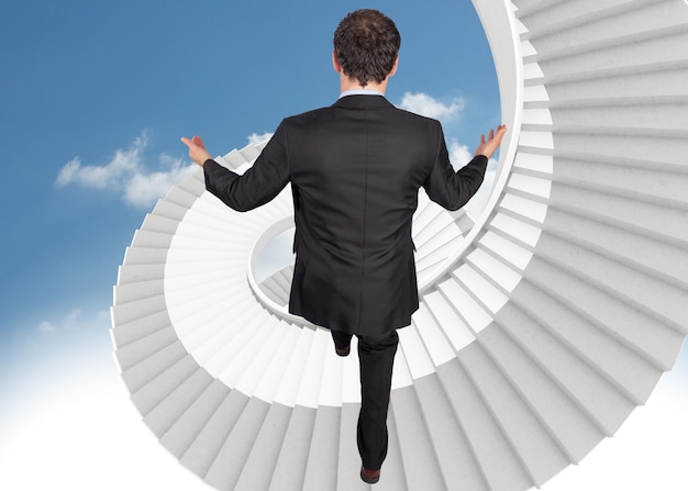 Photo businessman posing with arms out against spiral white stairs in sky