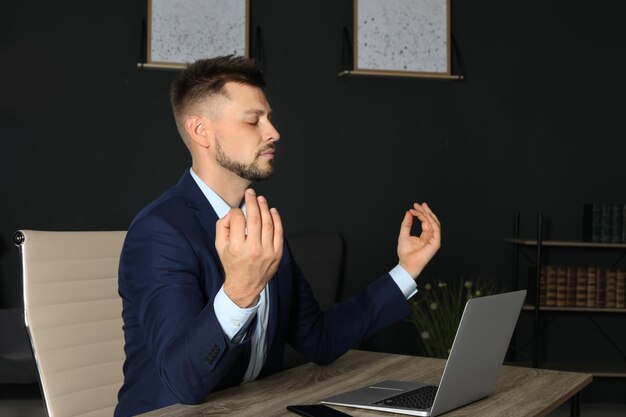 Photo businessman practicing zen yoga at table in office