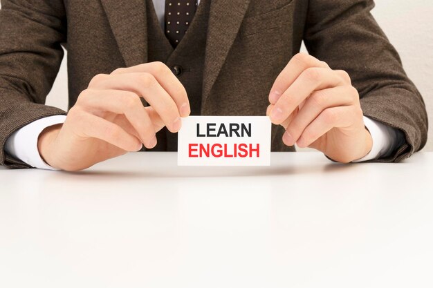 Businessman presenting 'LEARN ENGLISH' word on white card