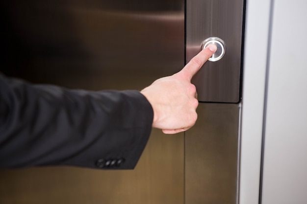 Businessman pressing elevator button in office